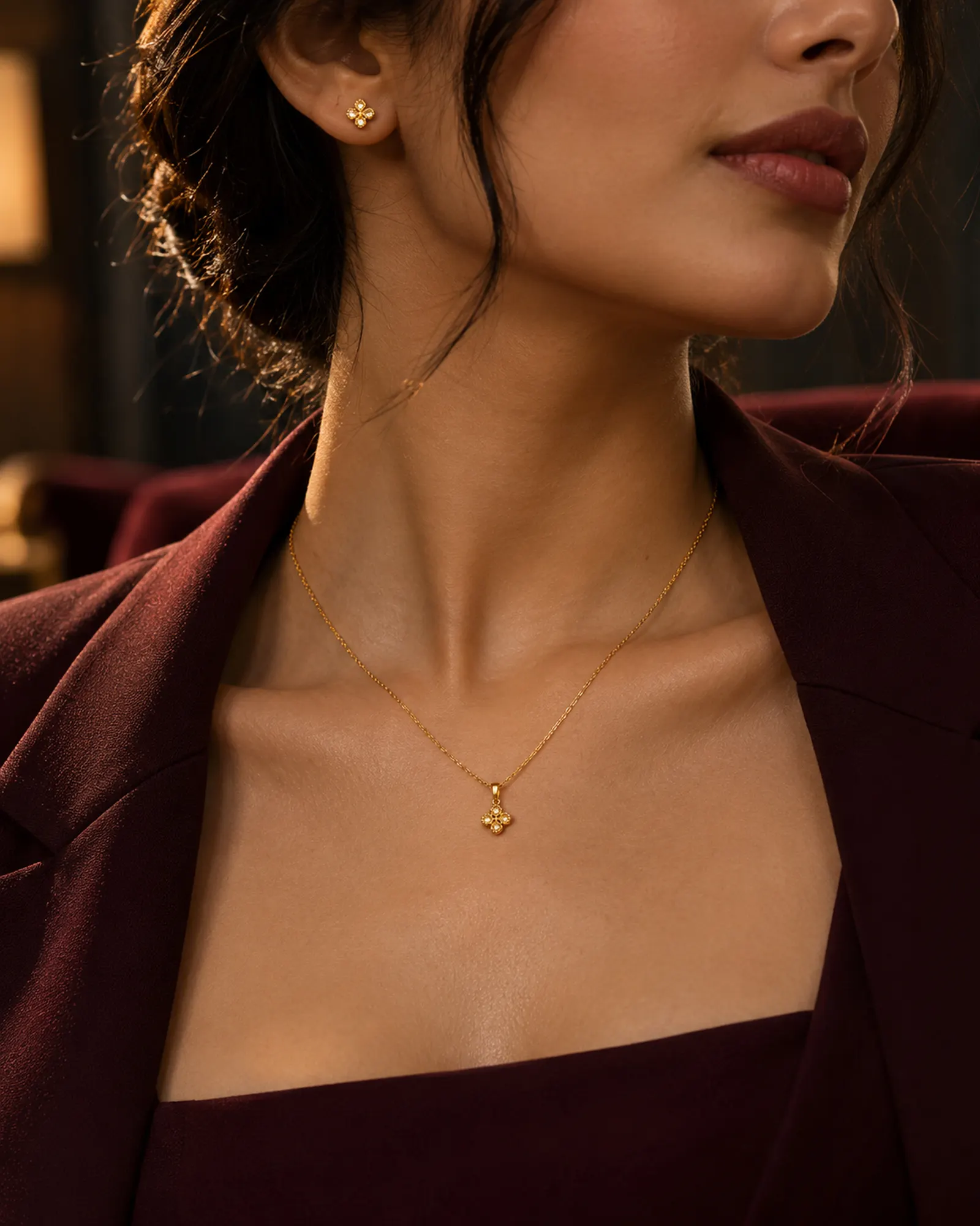 A thin gold chain and stud earrings worn at the collarbone